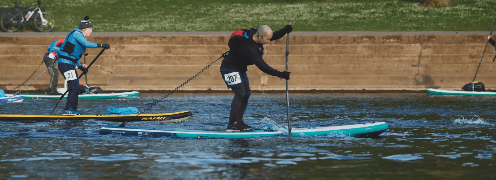 People stand up paddleboarding in a race