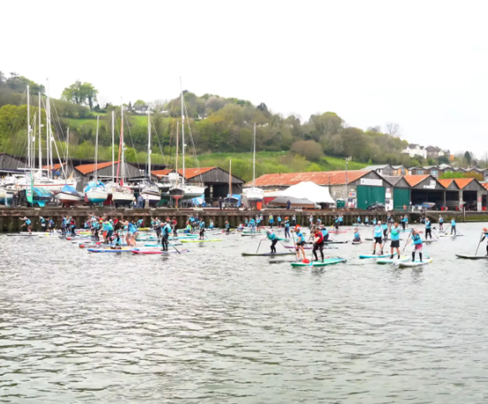 A group of people competing in a paddleboard racing event