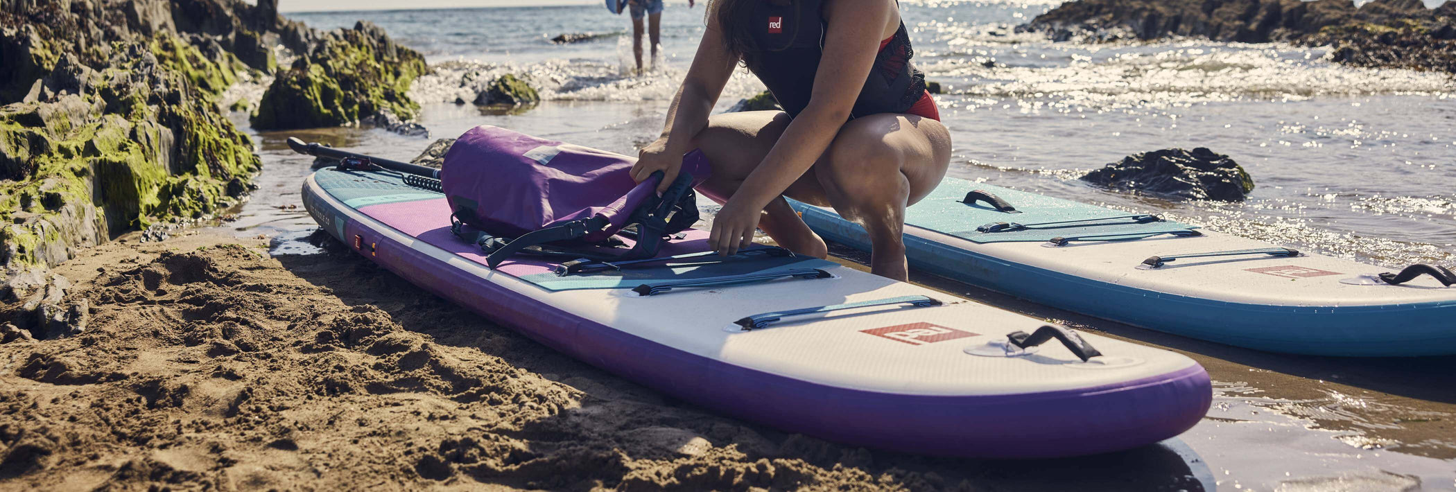 woman clipping bag onto inflatable paddleboard