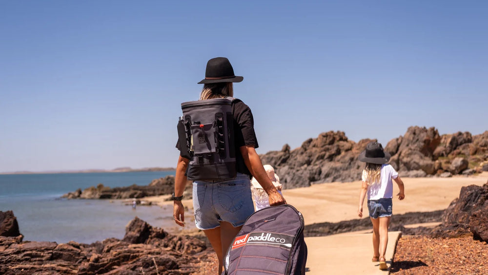 Woman walking carrying Red Original waterproof cool bag backpack in grey