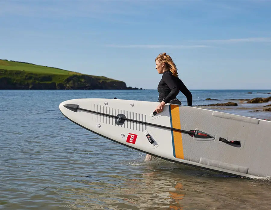 A woman carrying her paddleboard into the ocean