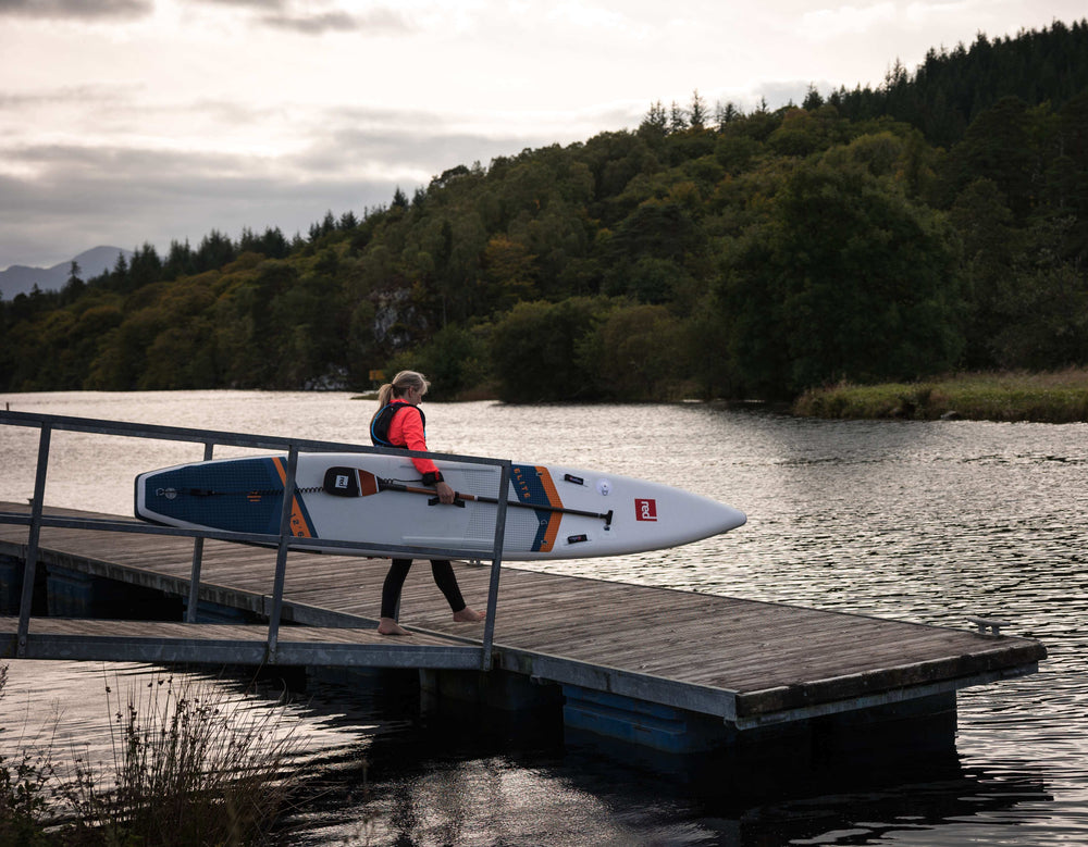 woman entering water with elite racing paddleboard