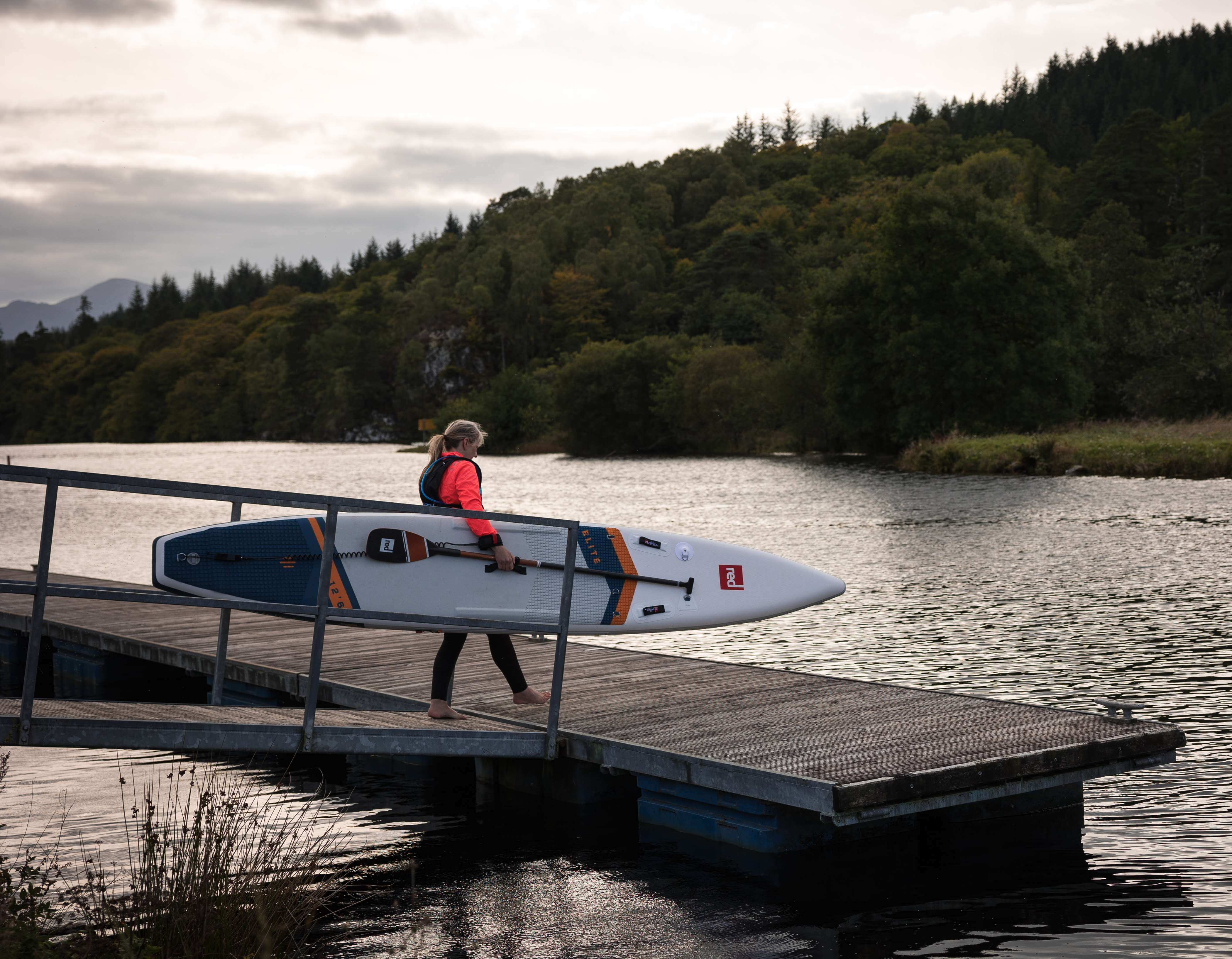 woman entering water with elite racing paddleboard