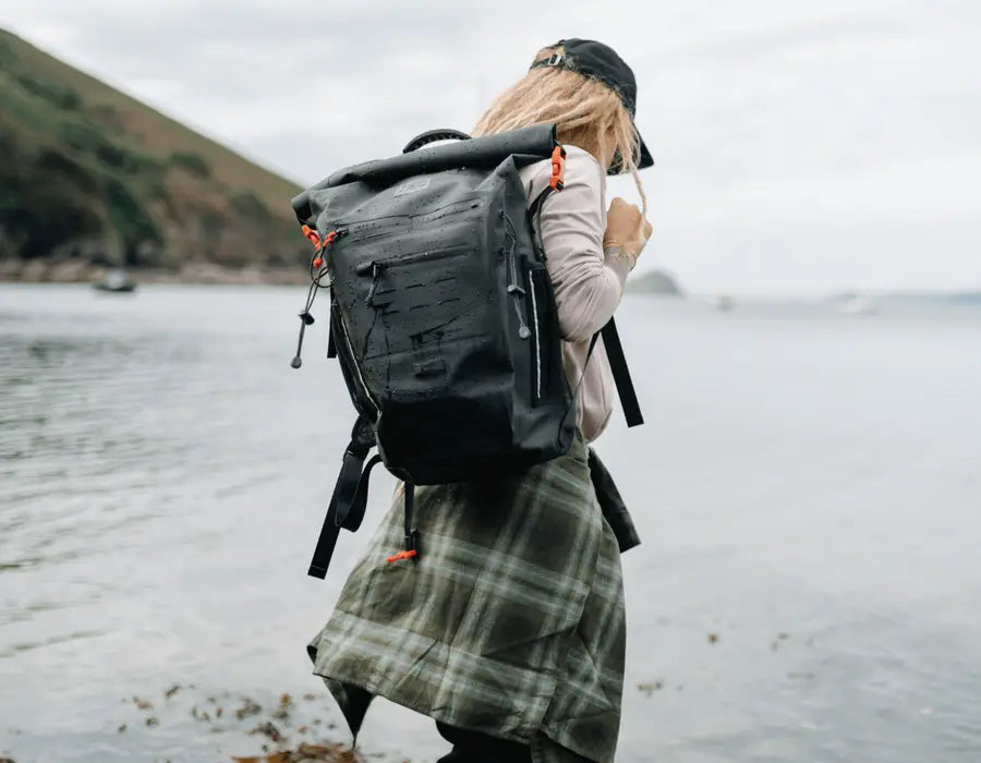 A woman carrying a Red Waterproof Backpack along the beach