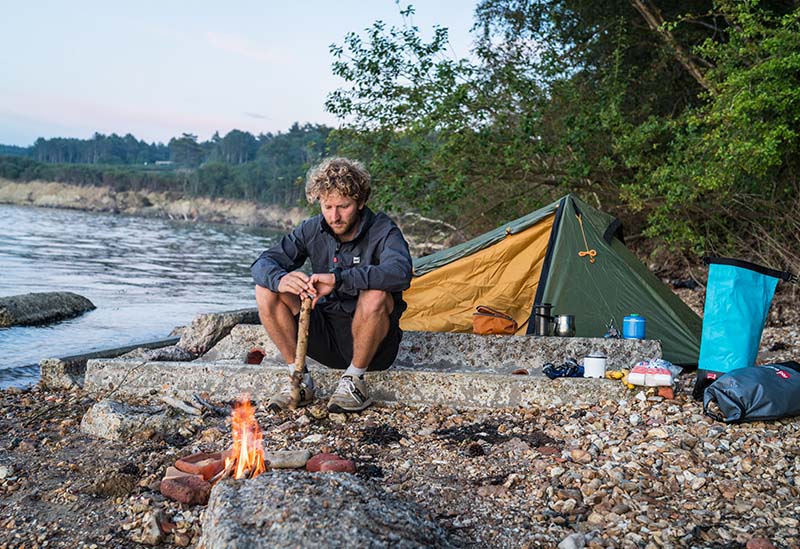 man camping next to body of water