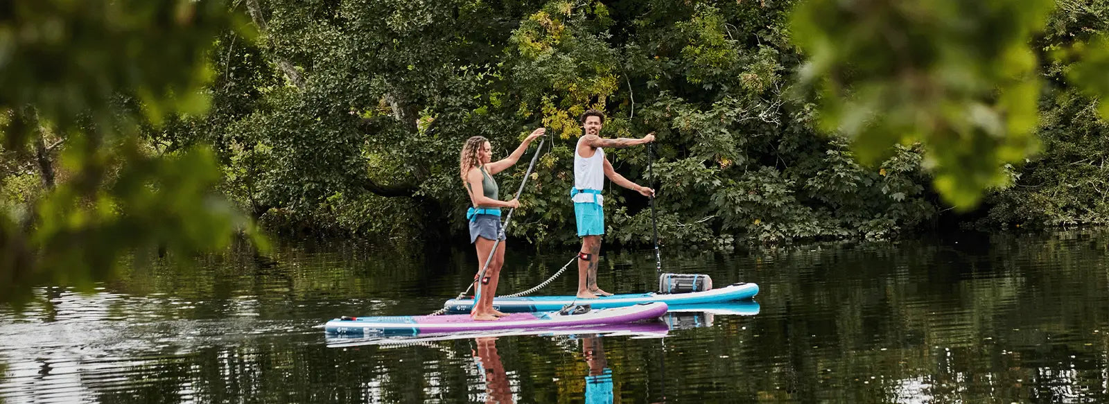 2 people stood up paddleboarding on a river