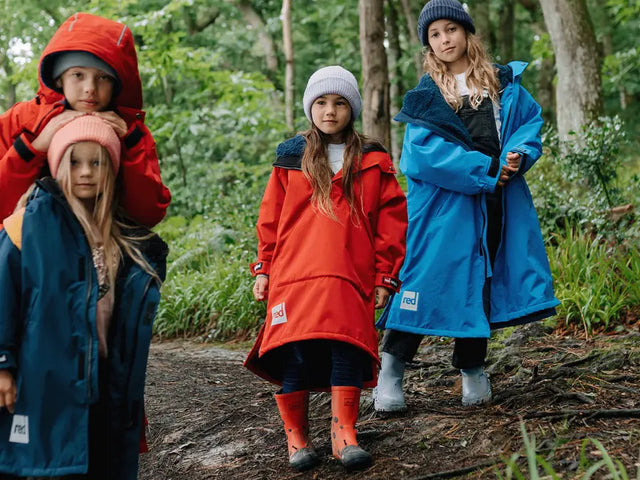 4 children wearing the Red Kids Pro Change Robe in the woods