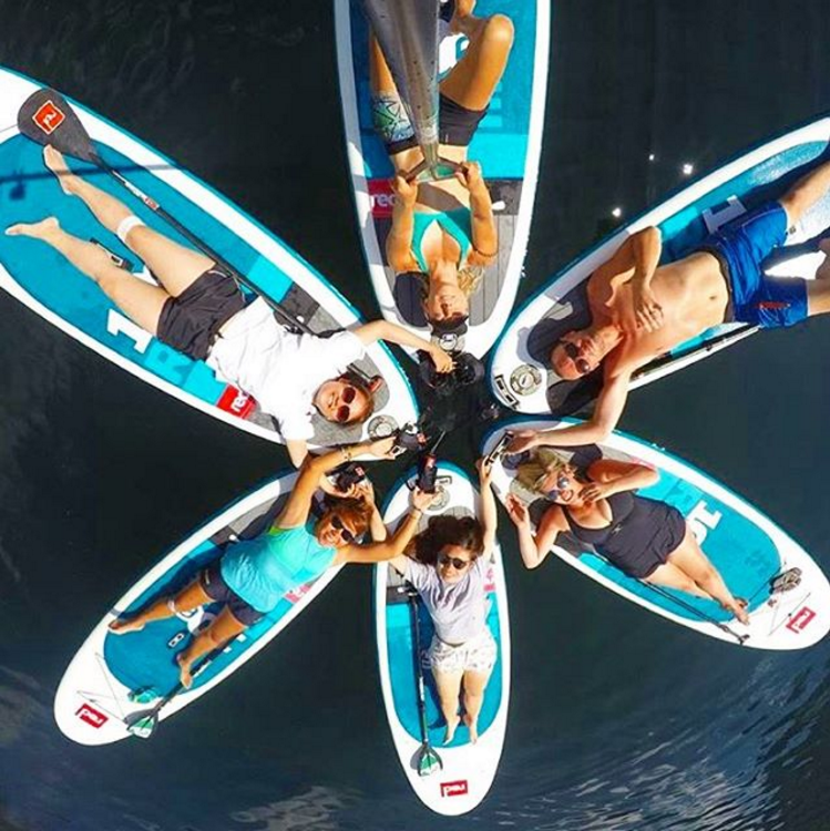 A group of paddleboarders lying on their paddleboards in a circle