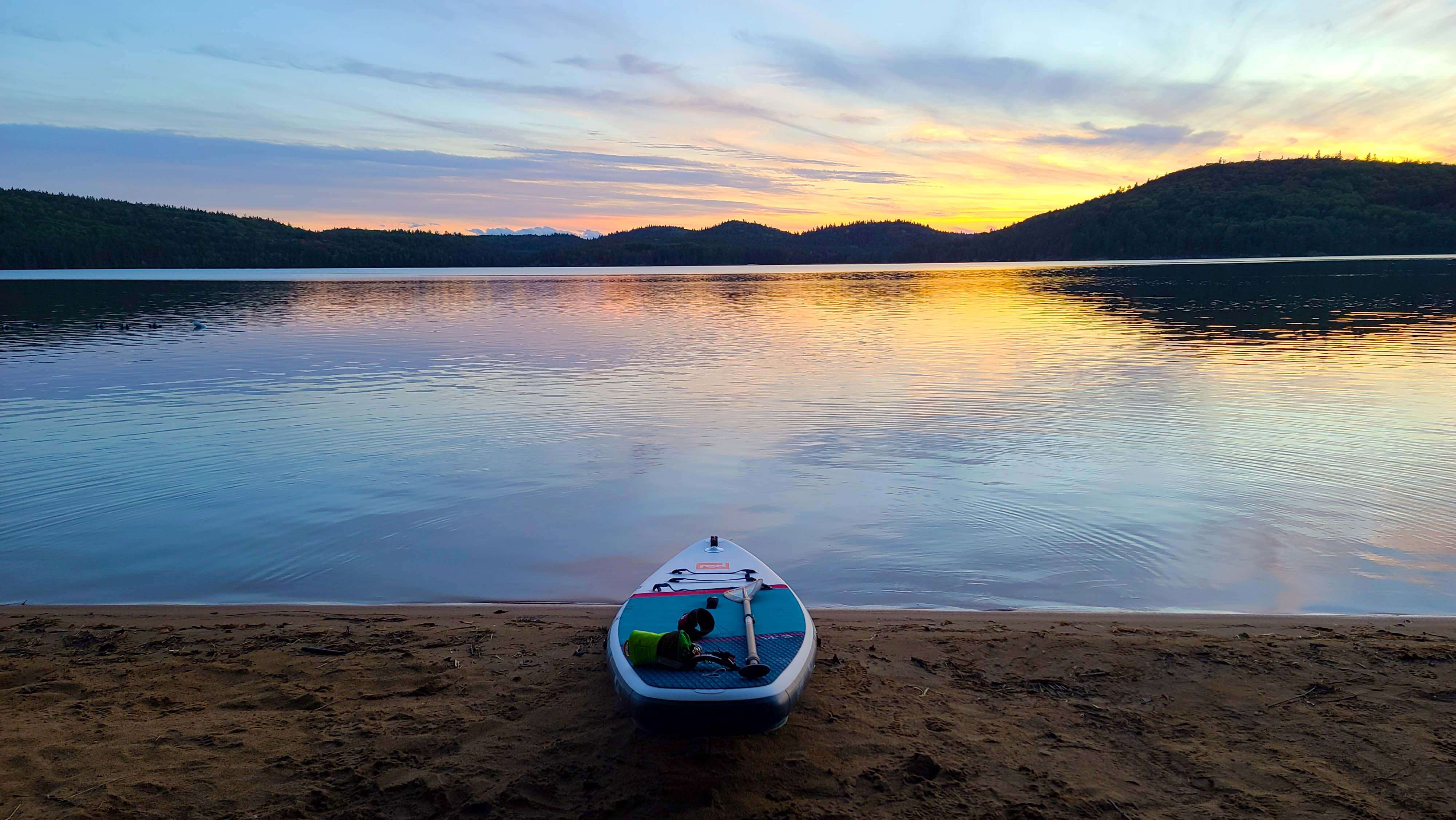 picturesque view of lake at sunset with Red inflatable paddle board on the shoreline