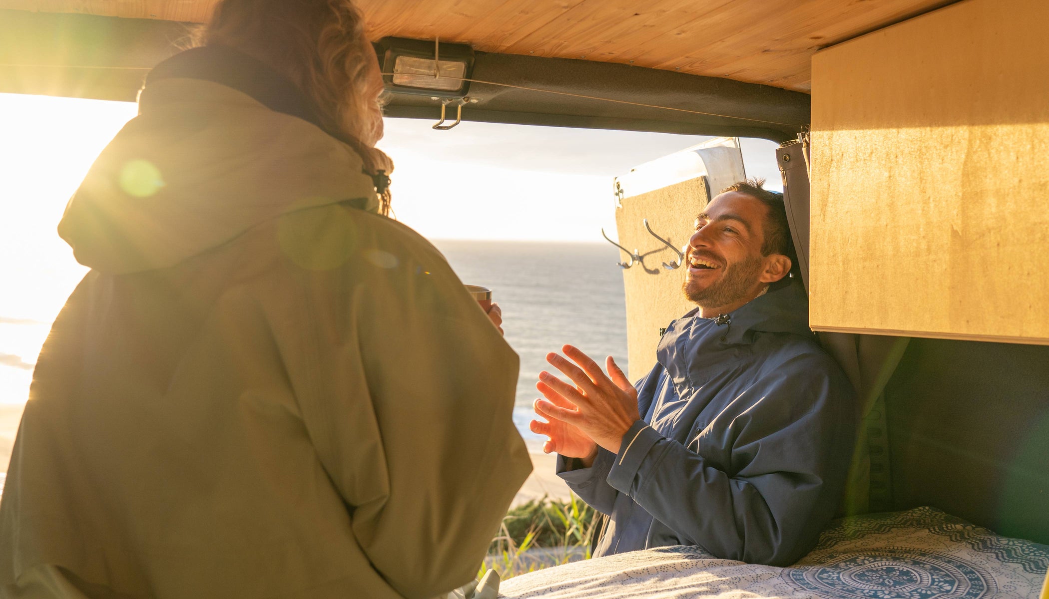 man and woman laughing in campervan wearing red original changing robes