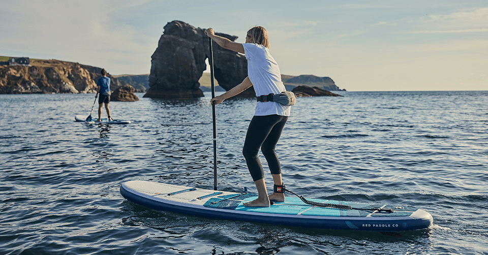 Two people paddle boarding using Red Original coiled leg ropes