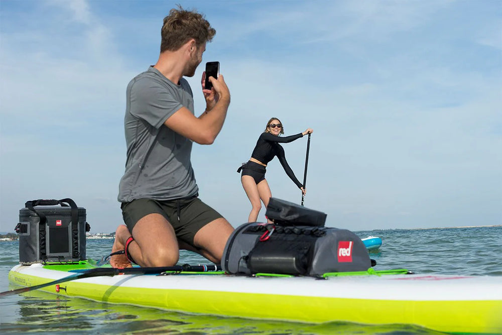 men and women on paddleboard with dry bag