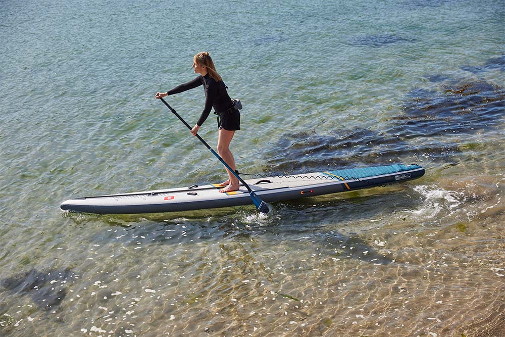 Woman standing on Red Original SUP using prime lightweight paddles