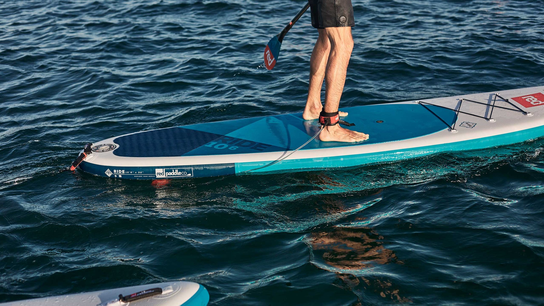 Man paddling using Red Original straight SUP leash