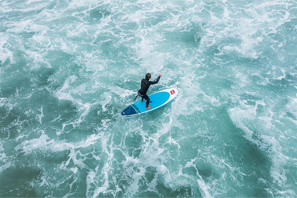 Person paddleboarding using Red Paddle Co board