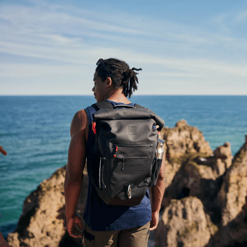 A man wearing a backpack, looking out to the sea