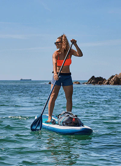 A woman stand up paddleboarding in the sea on a sunny day